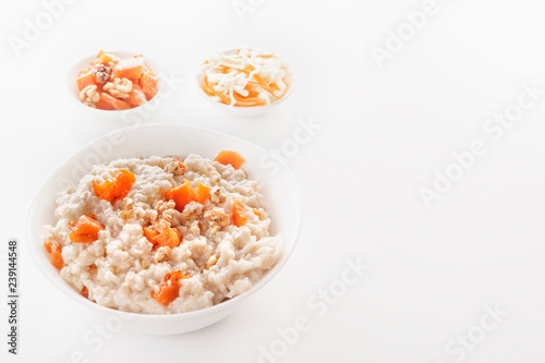 Oatmeal with pumpkin and nuts in a plate and vegetable salads on a white background. Close-up. Copy space