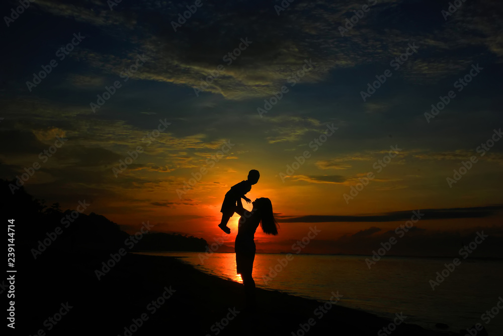 mother and daughter silhouette playing on the beach