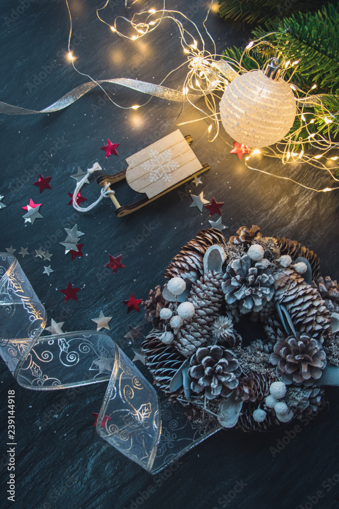 Naklejka premium Christmas decorations, fur-tree branches, colorful balls, garlands, red and white glittering stars, christmas wreath on a dark background