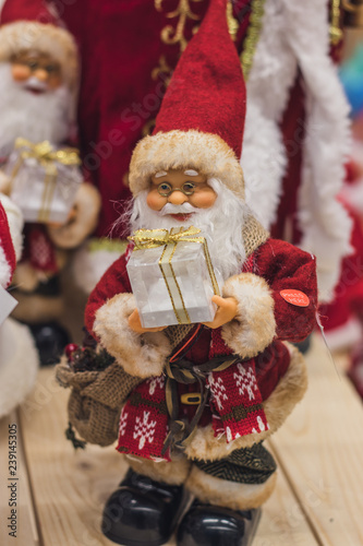 Santa Claus as Toy in red suit costume in a cap and gold-rimmed glasses with a blush on the cheeks carry gifts sale  market  realization in the shop
