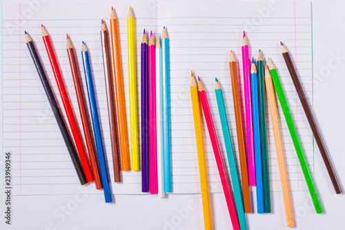 Цветные карандаши на белом листе тетради.
