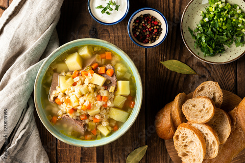 Rassolnik - Traditional Russian soup with pickled cucmbers, pearl barley, meat, pickles, carrots and potatoes on a dark wooden background. Top view photo