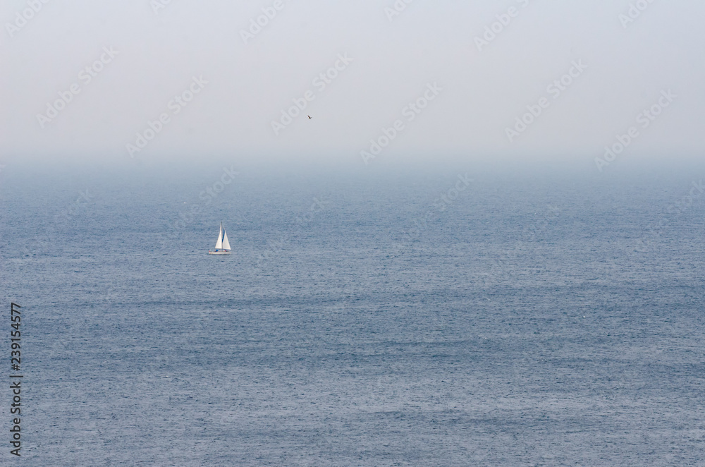 Sea scape with foggy atmosphere and sailing boat