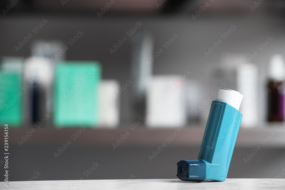 Asthma inhaler on table against blurred background. Space for text