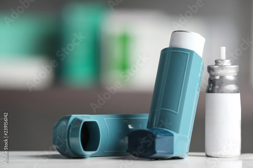 Asthma inhalers on table against blurred background. Space for text photo