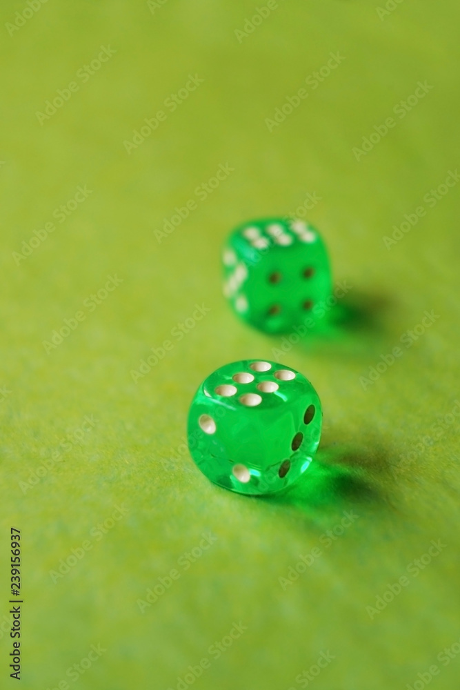 A vibrant monochromatic macro with depth of field about two green glass gambling dice with two lucky number six on green background. A vibrant monochromatic macro with depth of field about two green glass gambling dice with two lucky number six on green background.