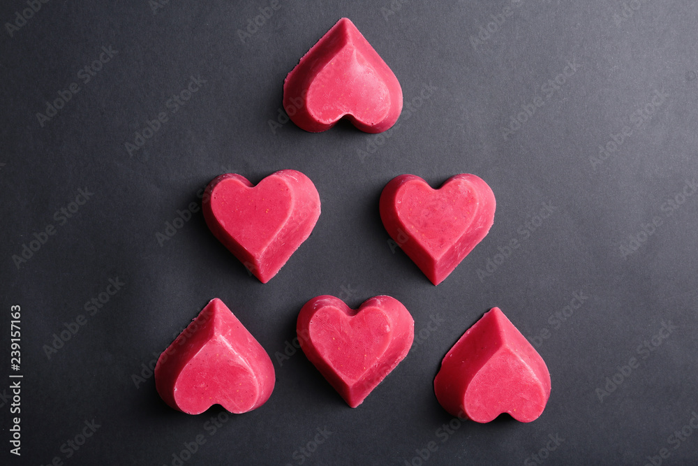 Fototapeta premium Heart shaped berry ice cubes on black background, flat lay