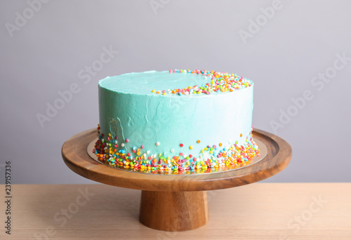 Fresh delicious birthday cake on stand against light background
