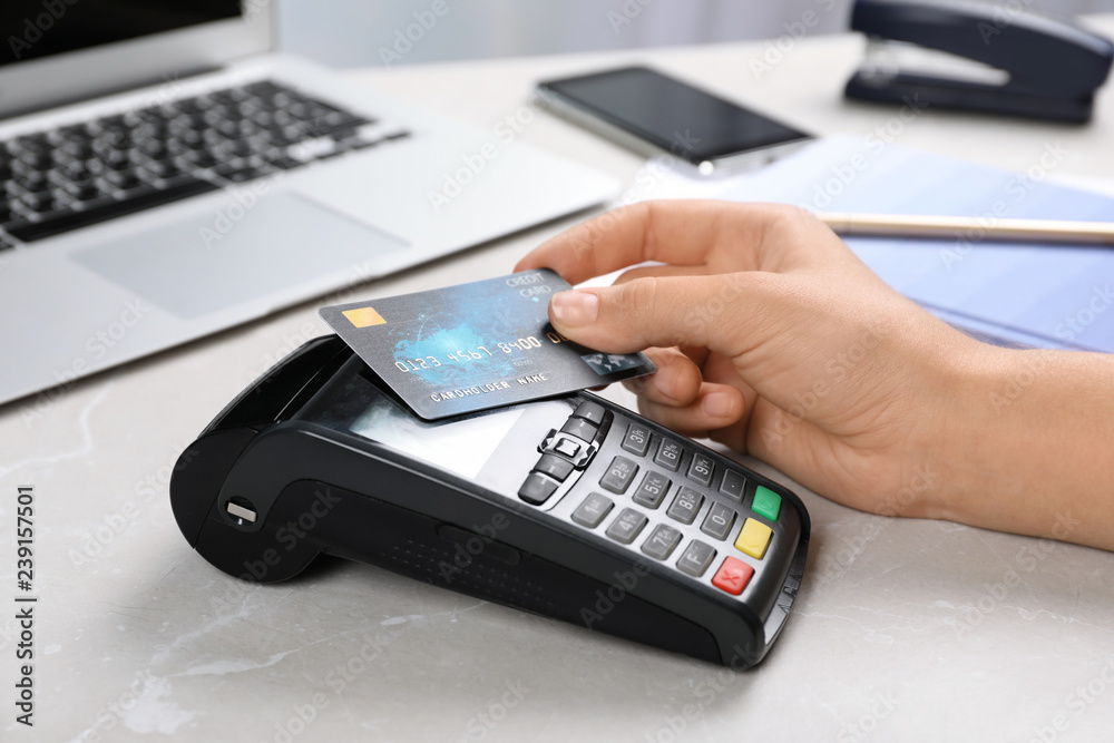 Woman using terminal for contactless payment with credit card at table Woman using terminal for contactless payment with credit card at table