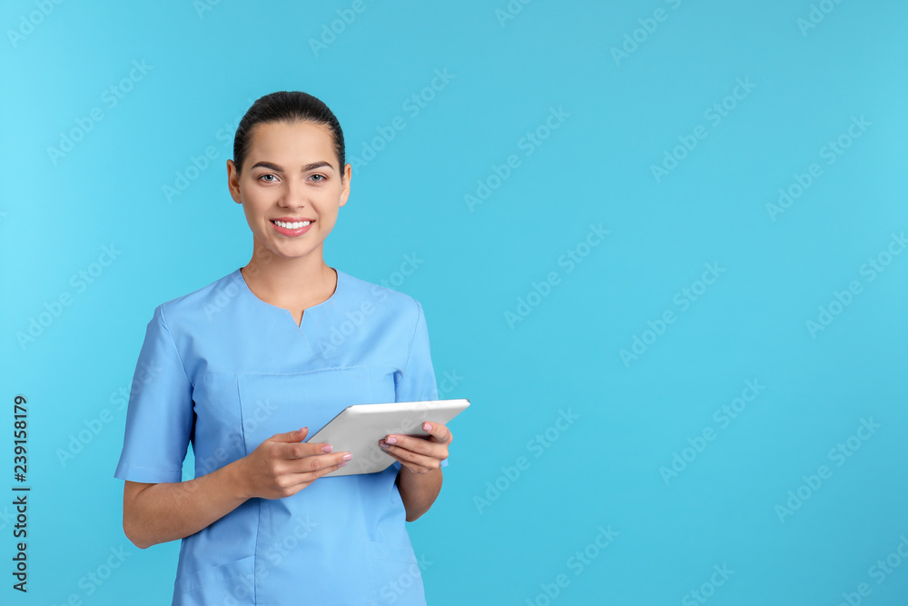 Portrait of young medical assistant with tablet on color background. Space for text - obrazy, fototapety, plakaty 