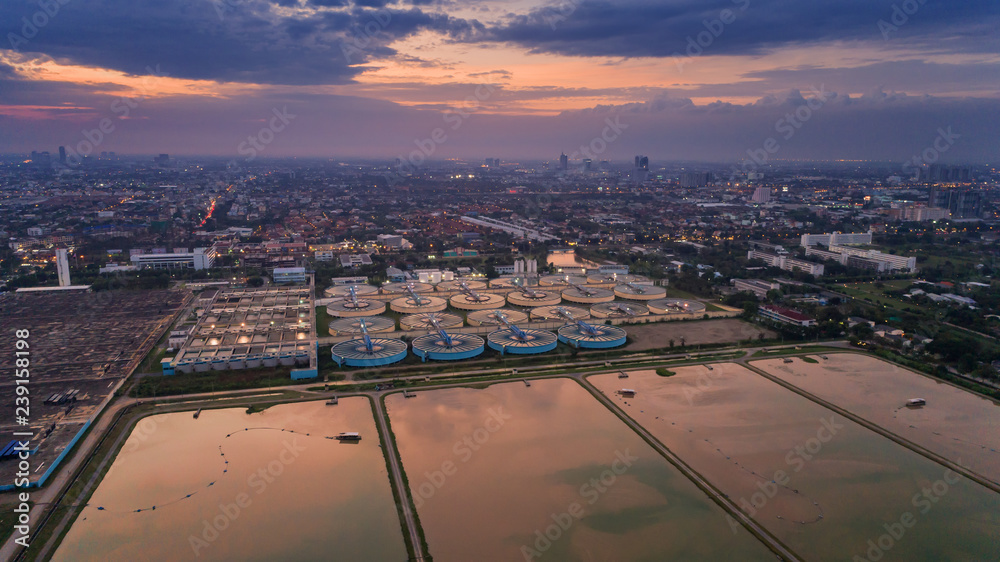 Aerial view water treatment plant at dusk with cityscape for environment concept.