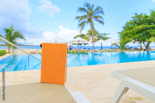 Yellow book on a sun lounger by the pool overlooking the sea. Holiday mood.