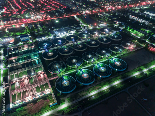 Aerial view water treatment plant at night with cityscape for environment concept.