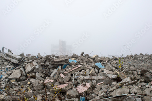 The remains of concrete fragments of gray stones on the background of the destroyed building in a foggy haze. Copy space