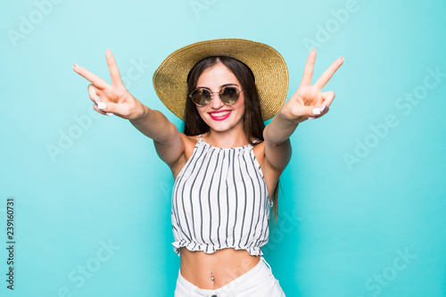 Portrait of a cute pretty woman showing peace gesture isolated over blue wall background.
