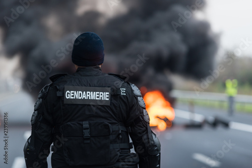 gendarme face à un feu de pneus lors d'une manifestation - blocage routier photo