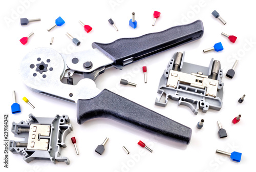 Crimping tool and electrical connectors isolated on white background closeup