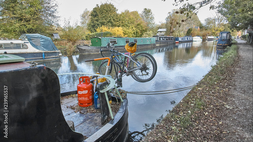 A boat moored on the Kennet and Avon Canal with rope bumper and chain and bicycle and propant canister or cylinder