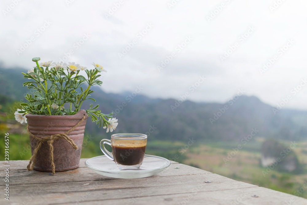 Morning cup of coffee and Flower Pot on the wooden table with mountain background at sunrise and sea of mist, image with copy space. Morning cup of coffee and Flower Pot on the wooden table with mountain background at sunrise and sea of mist, image with copy space.