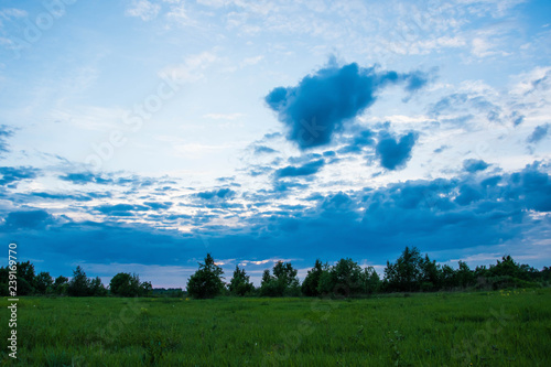 Dramatic and stormy clouds on the green field in summer