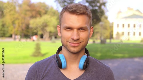 portrait handsome caucasian man with headphones posing outdoors. close up happy guy looking at the camera photo