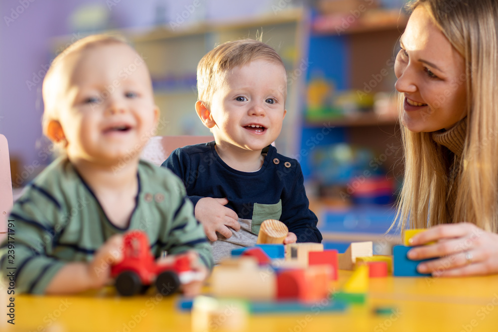 children group playing with teacher in day care centre playroom