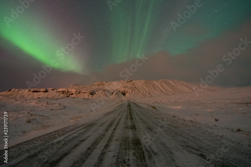 Northern Lights Aurora Borealis over icy road and mountain in Iceland