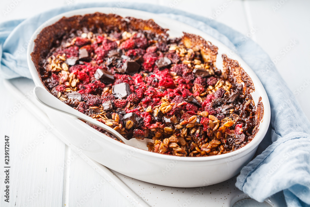 Baked oatmeal with berries and chocolate in a white dish. Baked oatmeal with berries and chocolate in a white dish.