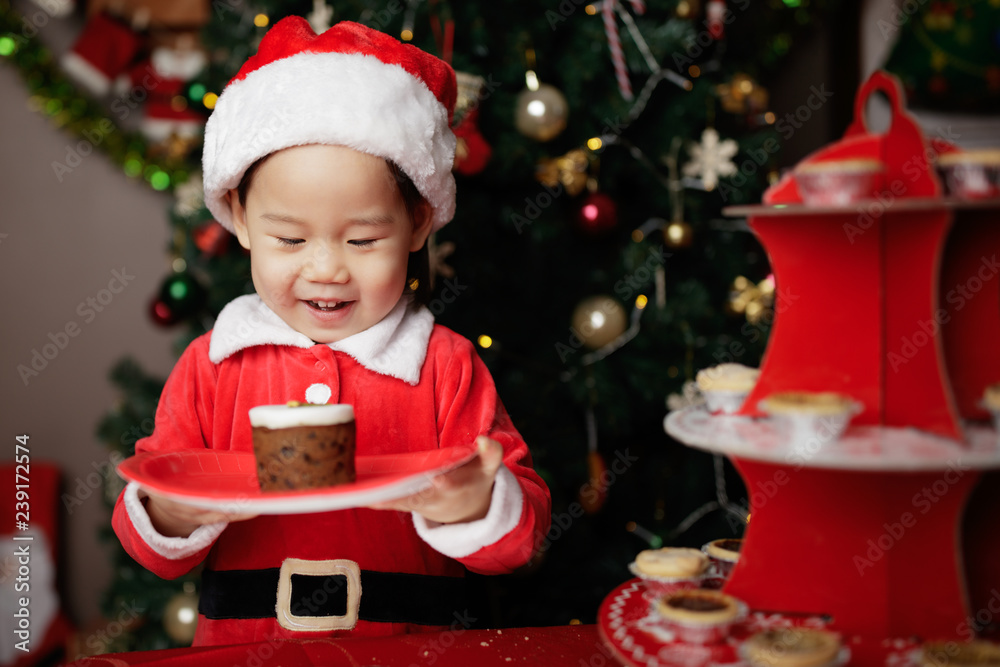 toddler baby girl eating Christmas cake in front of christmas tree toddler baby girl eating Christmas cake in front of christmas tree