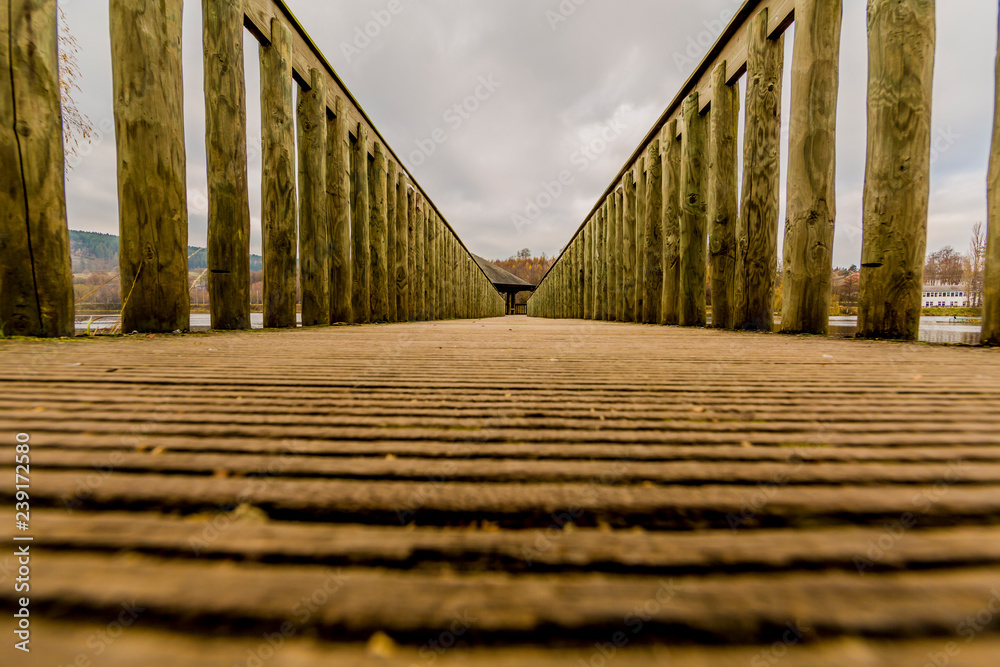 beautiful image of a way on a wooden bridge leading to a gazebo in the middle of the lake in Vielsalm in the Belgian Ardennes