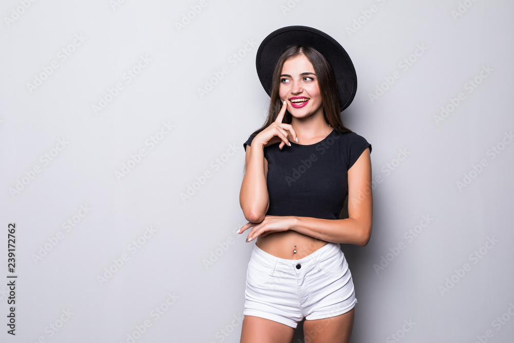 Portrait of young charming woman in hat posing and looking at camera isolated on a gray background Portrait of young charming woman in hat posing and looking at camera isolated on a gray background