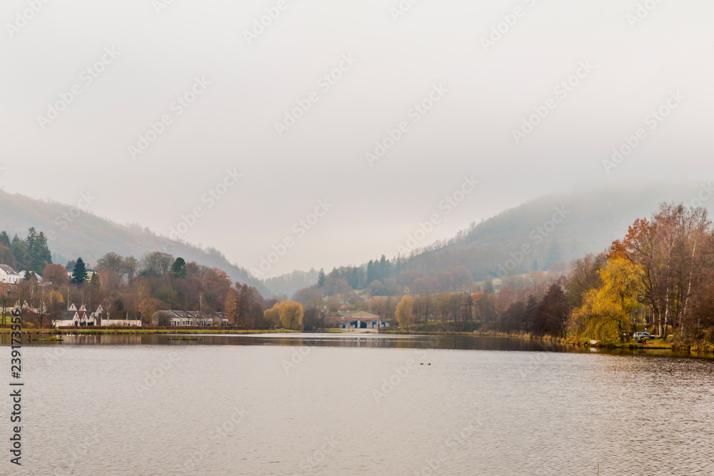 beautiful image of Doyards lake in Vielsalm with mist over the hills on a cold winter morning in the Belgian Ardennes