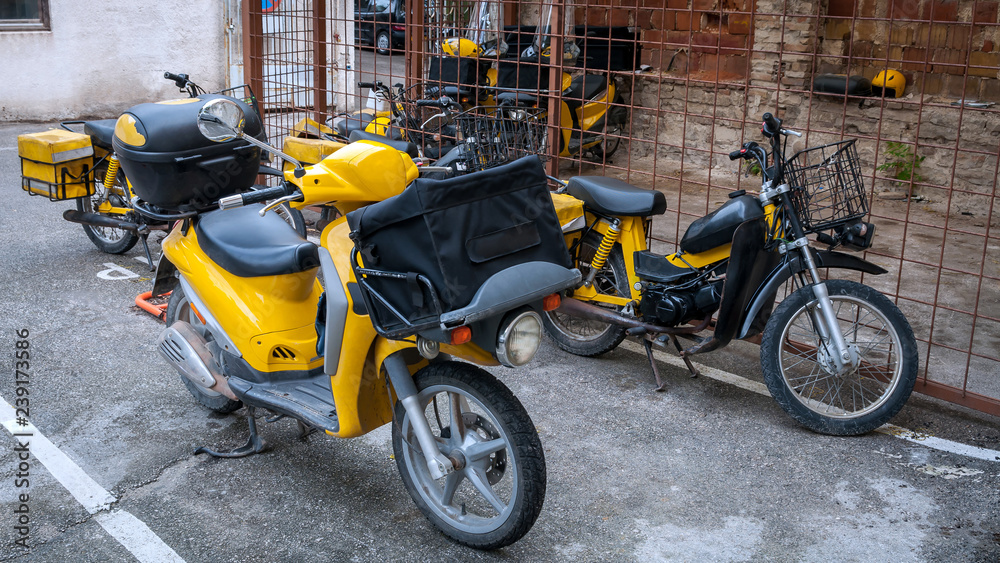 The group of yellow motorbikes with boxes for mail parked near the post office