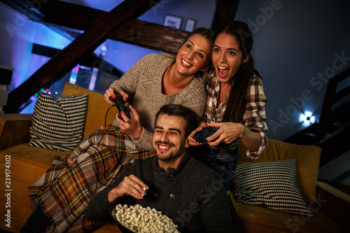 Group of best friends sitting at home on pleasant evening and playing games on console.They challenge each other to win .