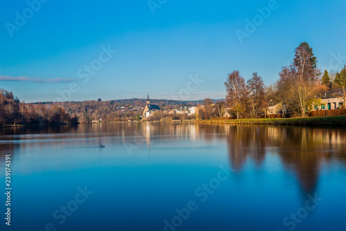 beautiful view of the Doyards lake with a wonderful reflection on the water and the village of Vielsalm in the background on a wonderful cold winter day in the Belgian Ardennes photo