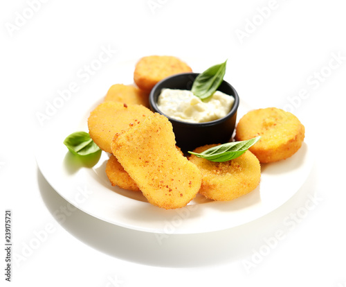 Fried chicken nuggets with white sauce and basil leaves on a white background.