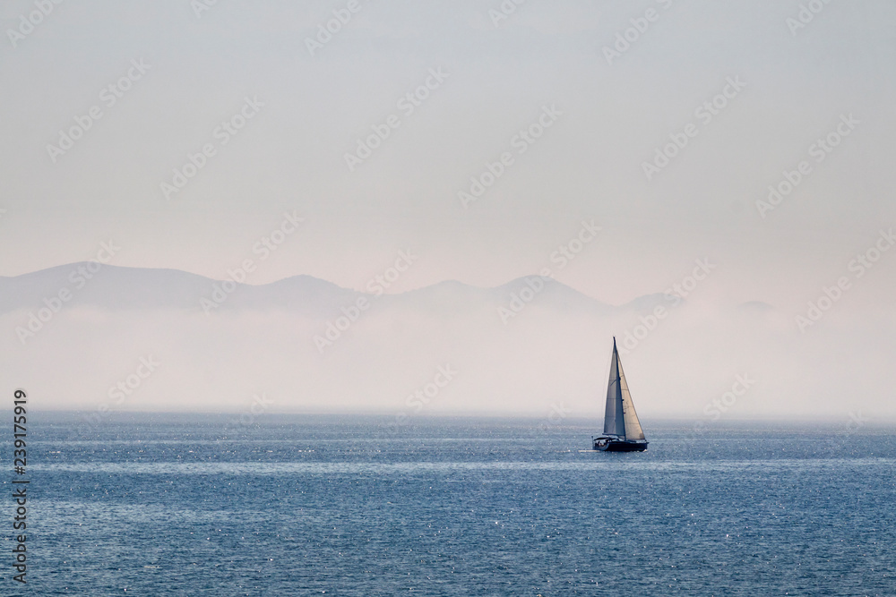 Misty morning on Adriatic sea in Croatia with islands and sailing boat