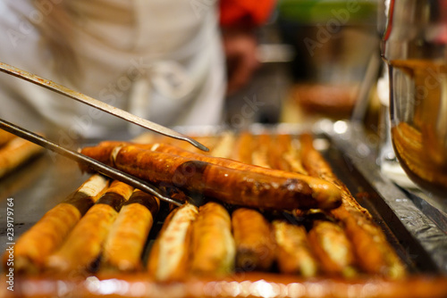 Group of bbq sausages cooking on grill. nipping sausage from grill.
