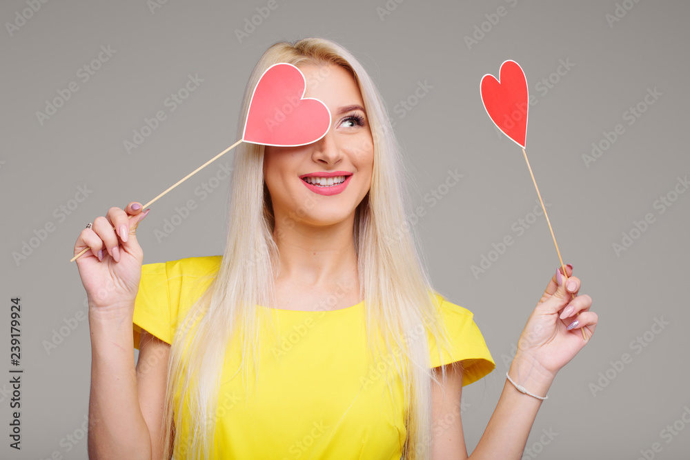 Valentine's Day. Beauty young blond model girl with Valentine red hearts on grey background. Copy space for text- Image Valentine's Day. Beauty young blond model girl with Valentine red hearts on grey background. Copy space for text- Image