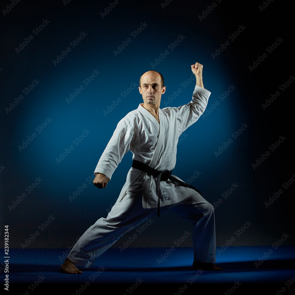 On the blue tatami man doing formal karate exercises On the blue tatami man doing formal karate exercises
