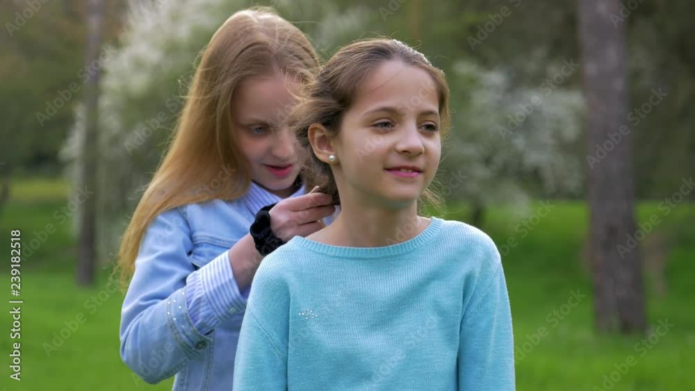 joyful little girl Plaits the Braid Of Her girlfriend. concept of friendship and relationships joyful little girl Plaits the Braid Of Her girlfriend. concept of friendship and relationships