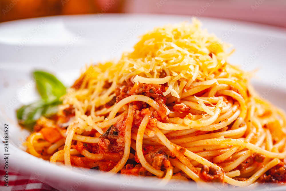 Italian cuisine. Spaghetti bolognese with meat, parmesan cheese and tomatoes on white plate. Close up