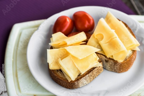 Snack with sliced cheese, bread and tomato.