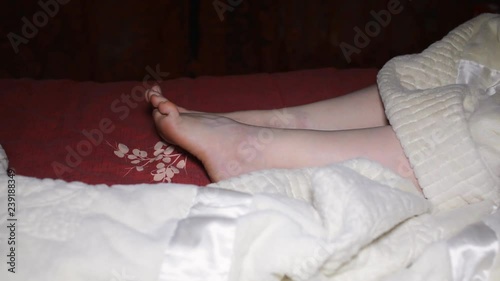 woman lying on the bed and rubbing feet together