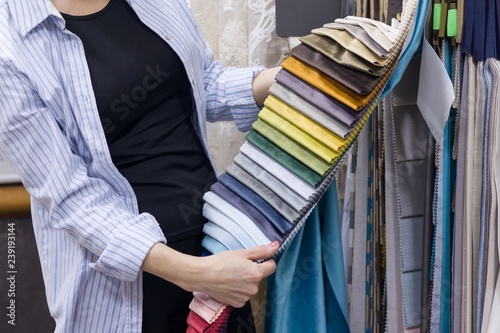 Fabrics Store, female looking and touching samples, female designer chooses fabrics for interior decoration