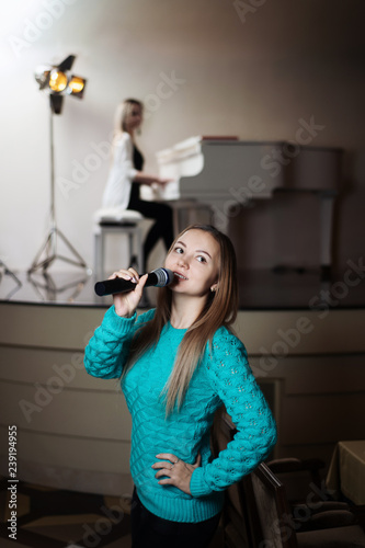 Girl sings in a restaurant, and behind her colleague plays the piano.