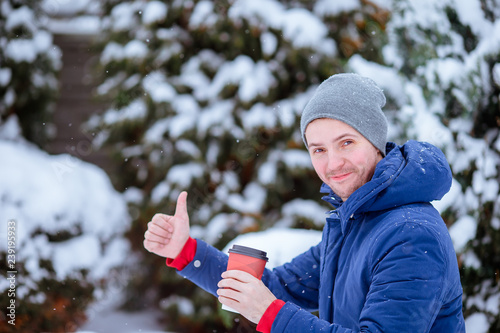 Happy man drinking coffee outdoors in winter time