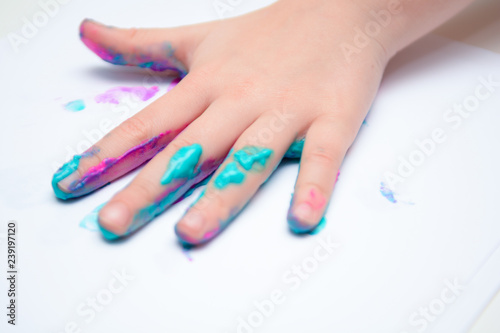 Happy child playing with paint, the girl has paint on hands and fingers