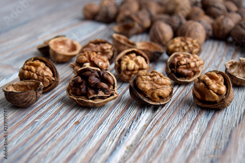 Walnuts are on a wooden surface. Walnuts are shelled. The edible kernel of nut is in a shell.