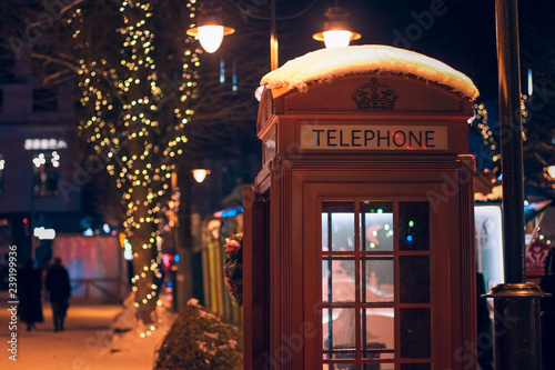 English red classic phone booth in Christmas urban street decoration object at night time with illumination 